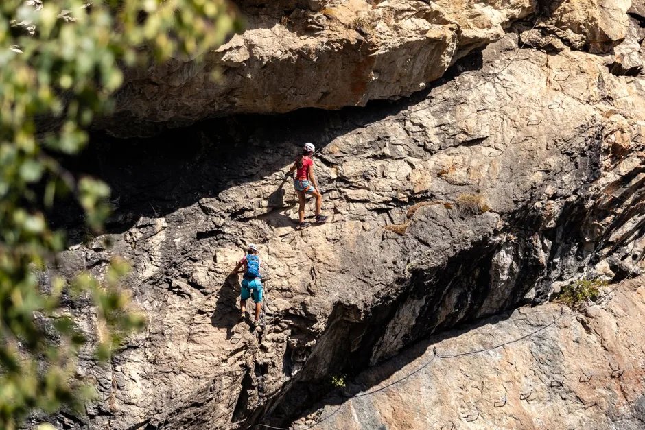 Débutant équipé d'un harnais et de longes progressant sur une via ferrata en paroi rocheuse